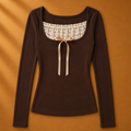Brown long-sleeve top with lace neckline and bow on a brown background